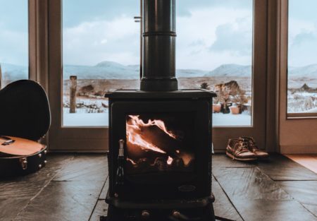 a black gas stove on a wood floor next to a window