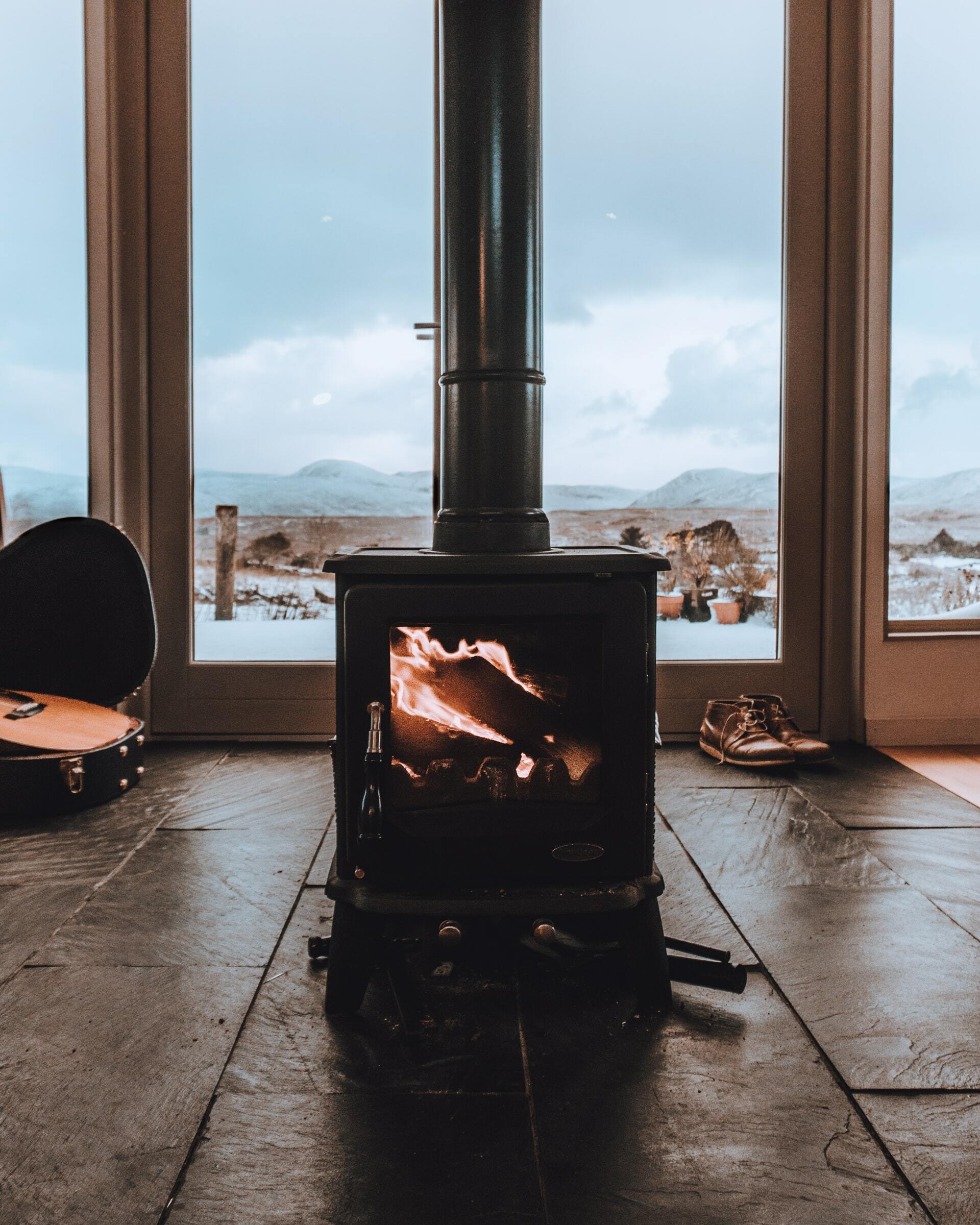 a black gas stove on a wood floor next to a window