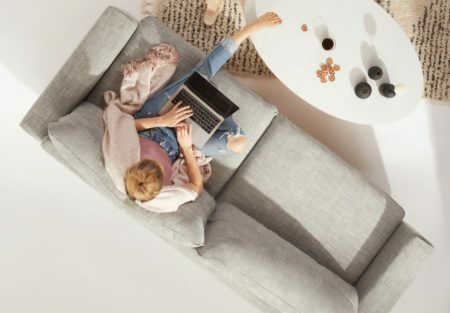 a man and woman sitting on a couch with a laptop