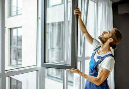 Workman-adjusting-window-frames-at-home-scaled