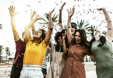 Group of friends enjoying party throwing confetti in the air - M